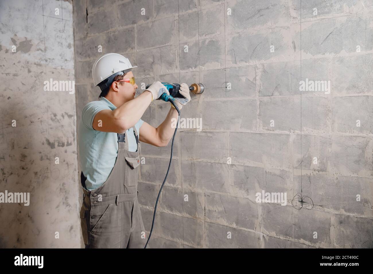 Builder worker pneumatic hammer drills hole in concrete brick wall with