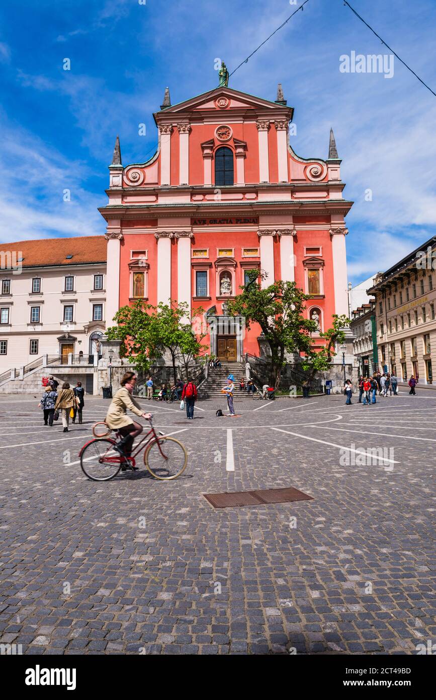 Preseren Square Tourist cycling past the Franciscan Church of the Annunciation in ...