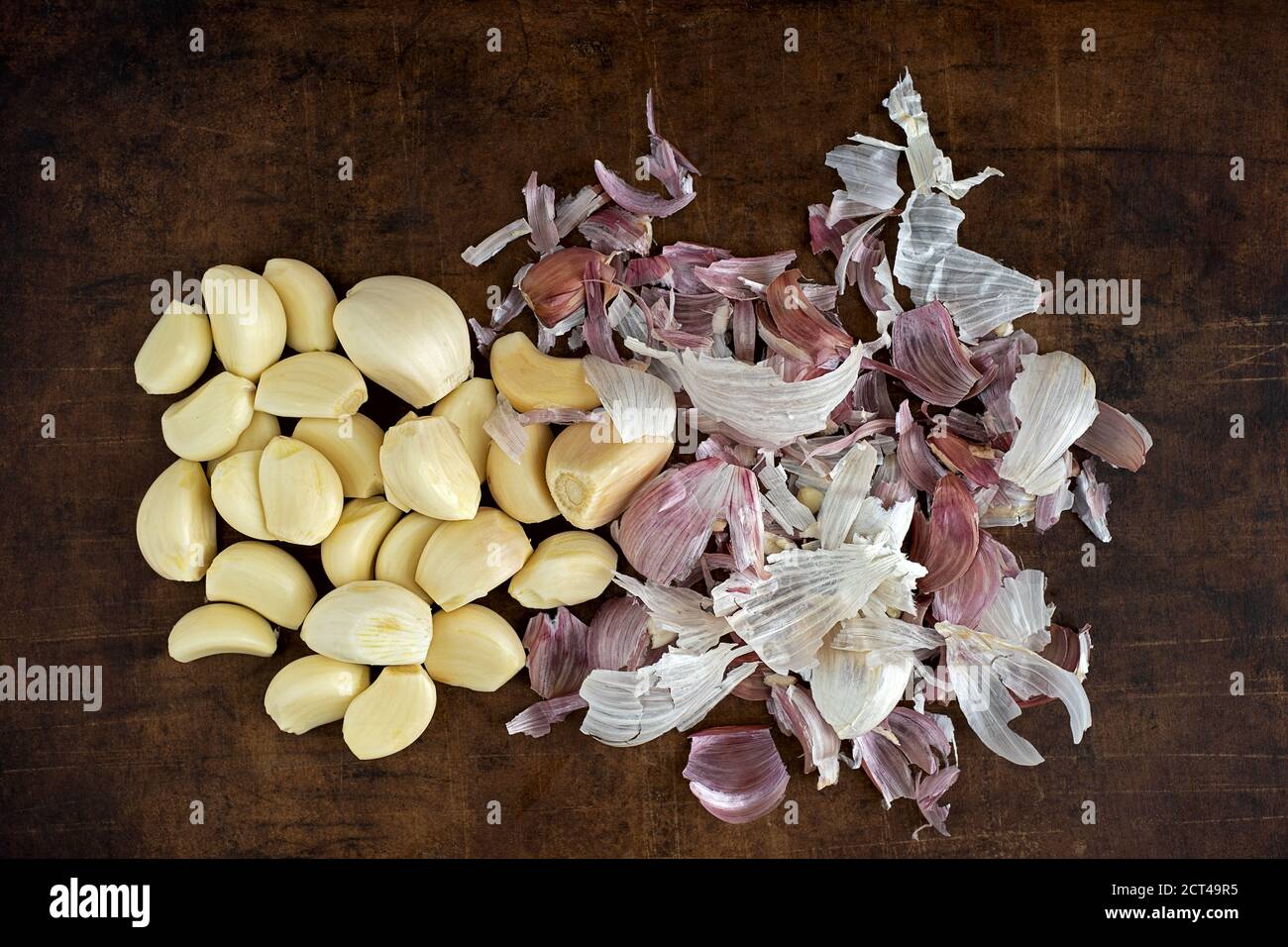 Garlic cloves prepared for cooking on a brown stoneware plate Stock