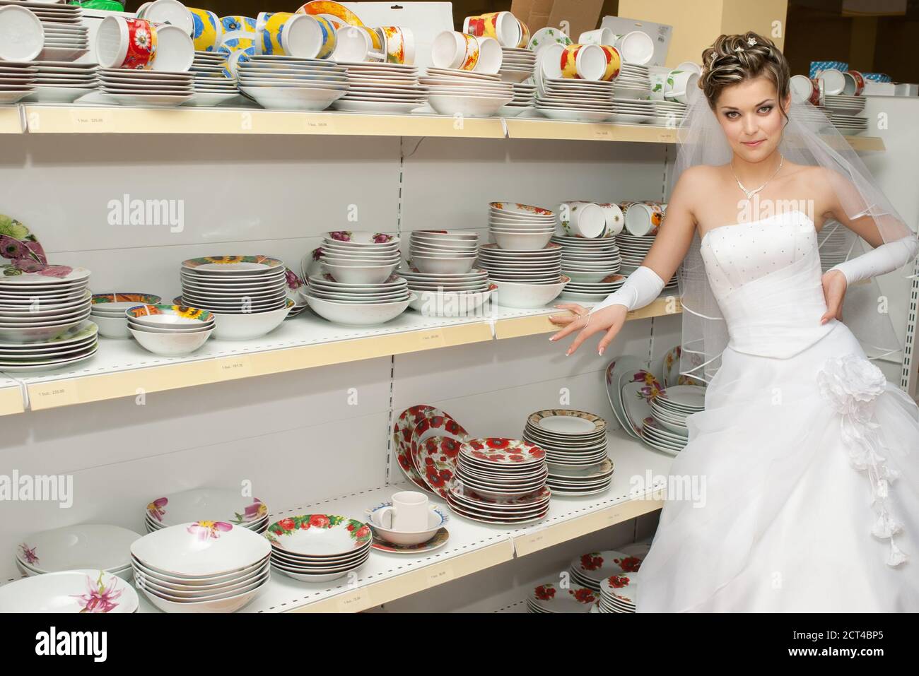 bride standing next to shelves with dishes and plates in kitchen