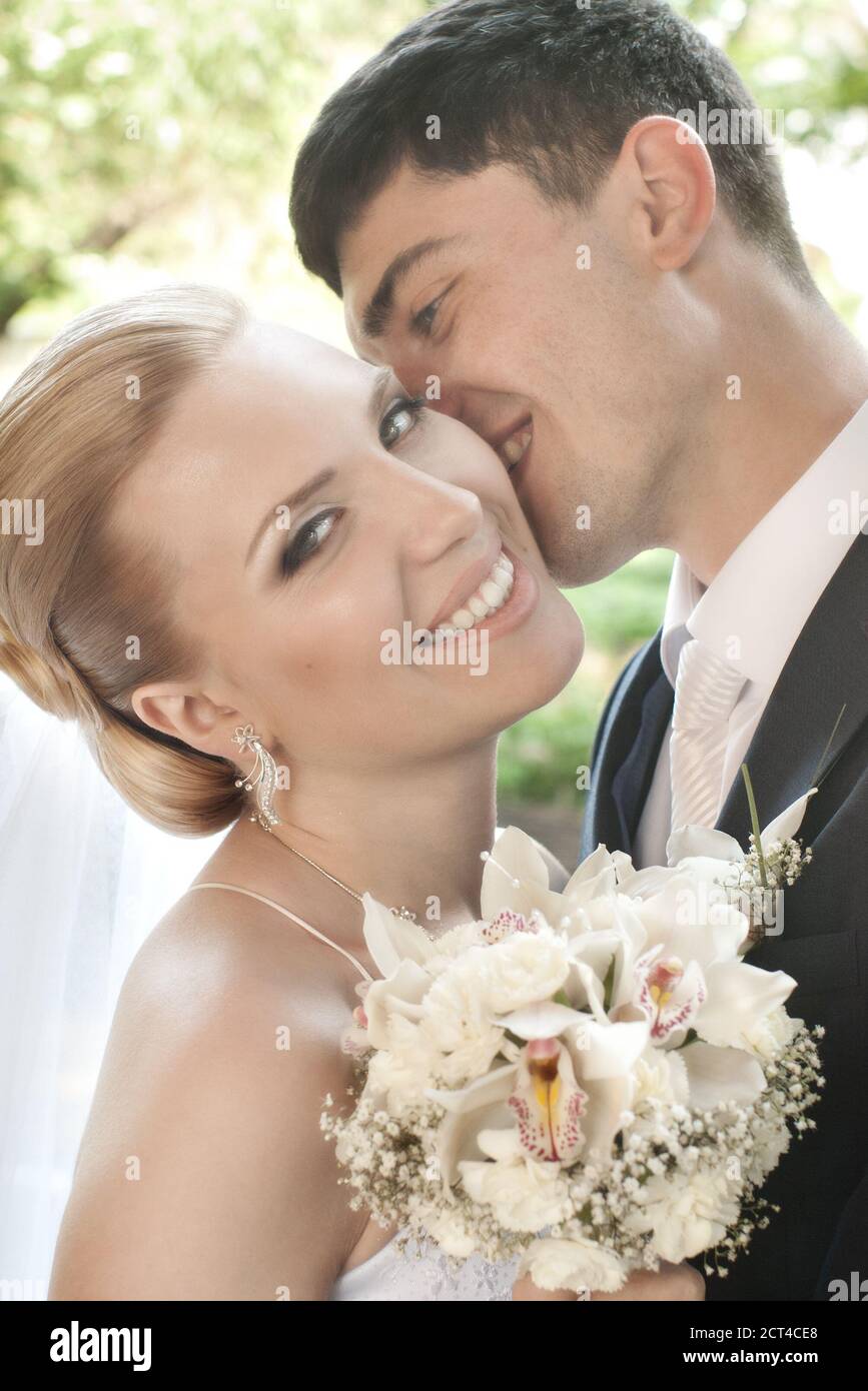 Happy bride being kissed in the cheek by groom with selective focus Stock Photo