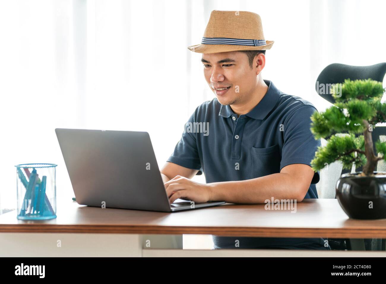 Online, remote job and lifestyle concept - happy Asian man with laptop computer working at home, Concept of technology communication Stock Photo