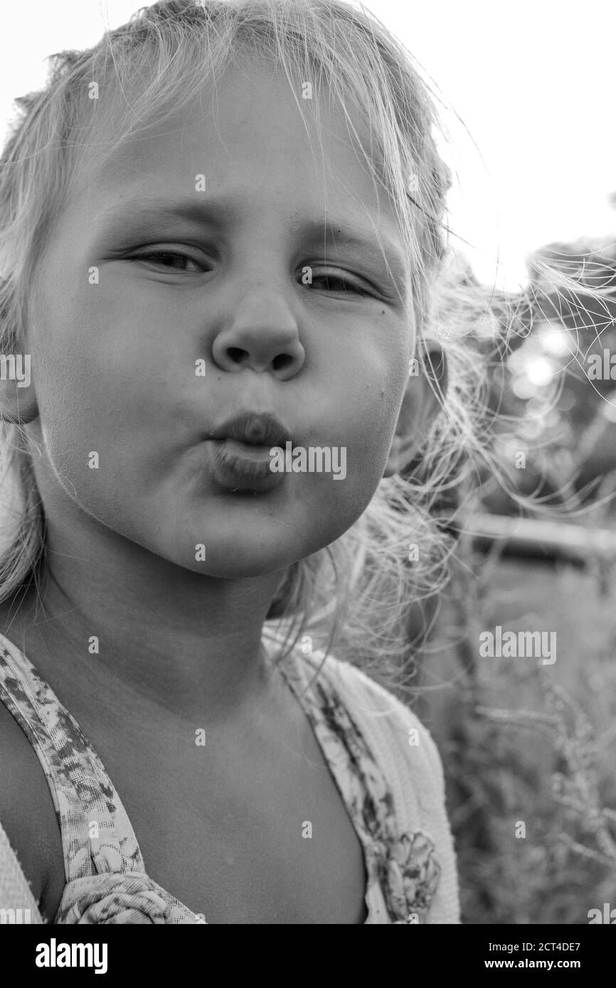 Close up black and white portrait of cute adorable smiling caucasian child. Portrait of a happy child in nature. Happy childhood concept. Baby kissing Stock Photo