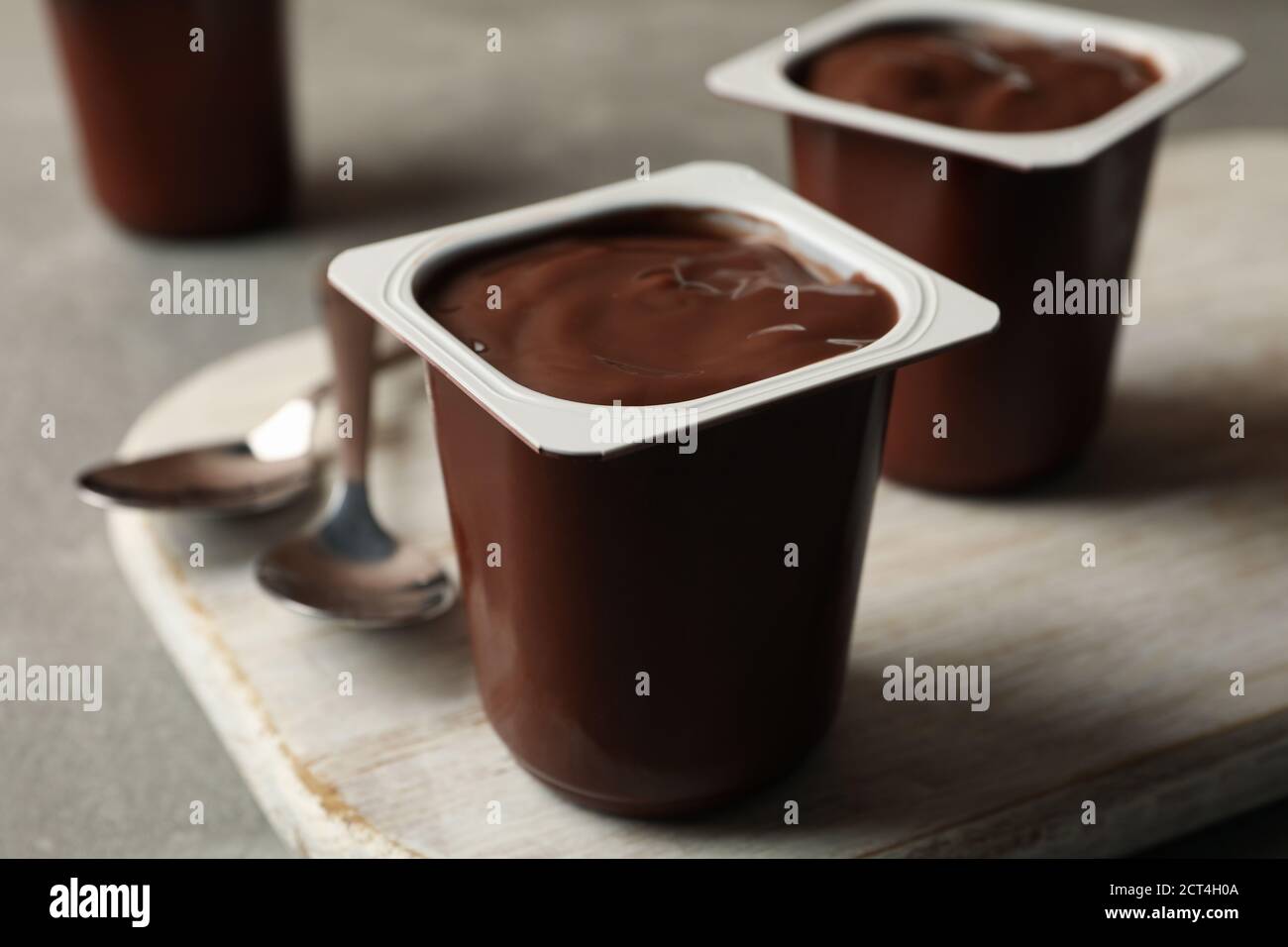 Board with plastic cups of yogurt and spoons on gray background Stock Photo Alamy