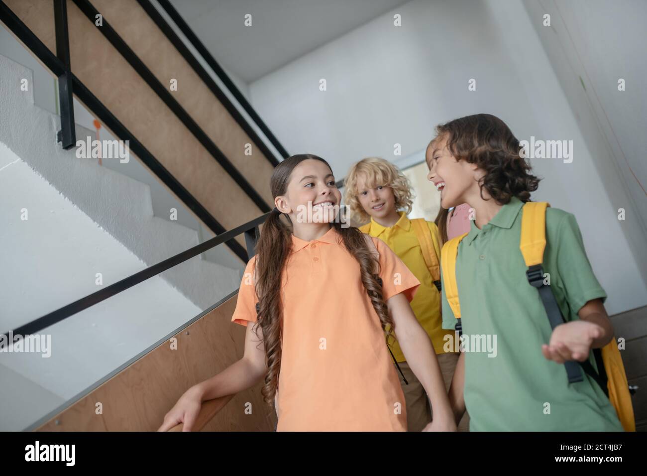 School friends going downstairs and talking and feeling good Stock Photo