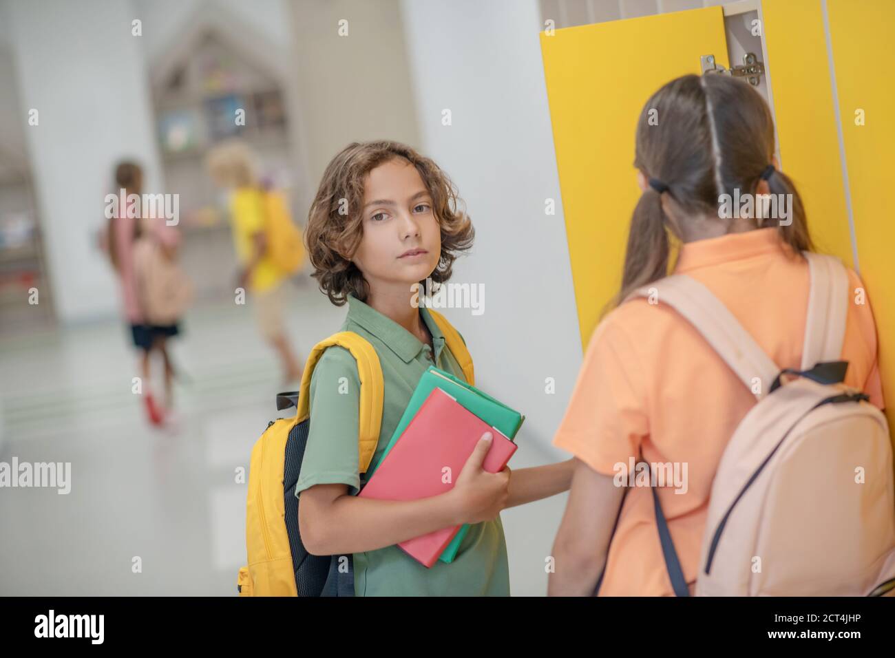 Dark-haired boy talking to his classmate in a school corridor Stock ...