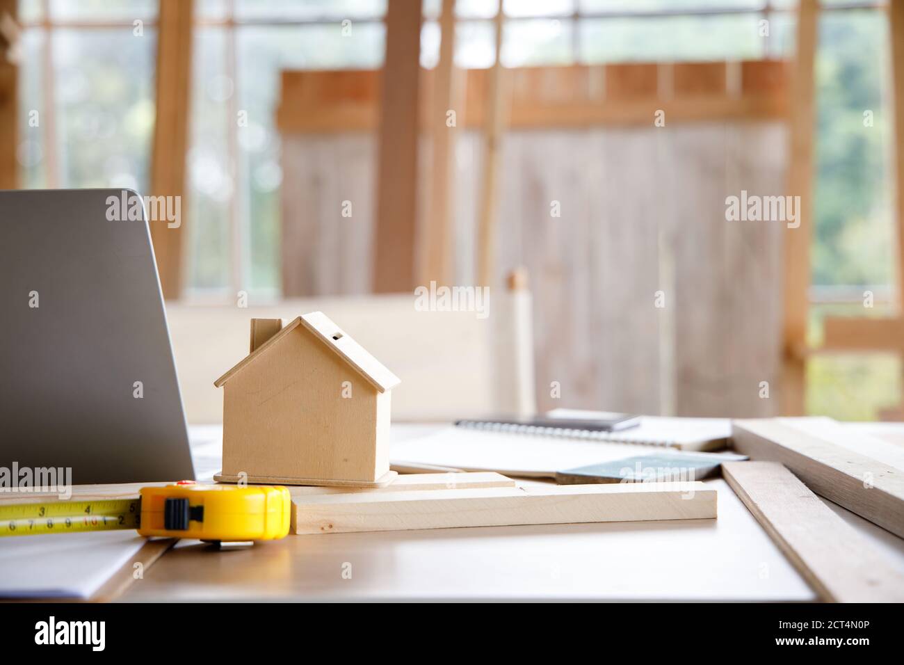 Tiny Wooden House On A Messy Table With Tape Measure And Laptop Computer Stock Photo Alamy