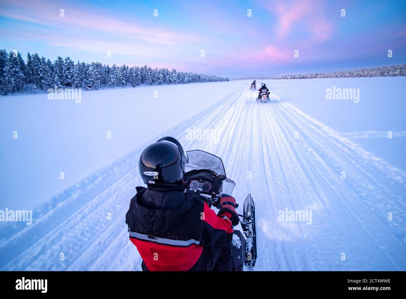 Snowmobiling on the frozen lake at sunset at Torassieppi, Lapland, Finland Stock Photo