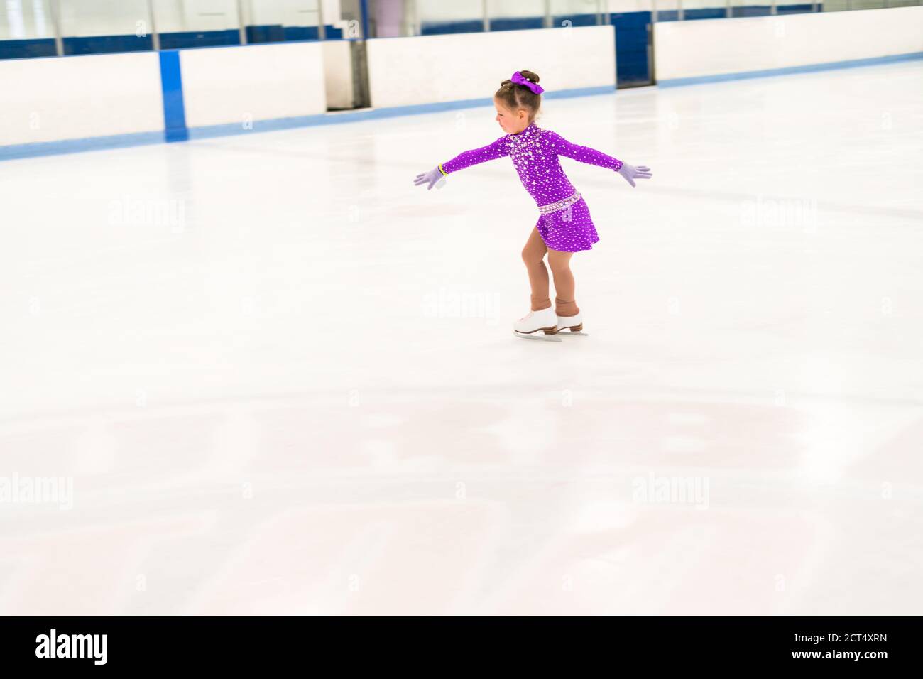 Little girl practicing figure skating in a purple dress with crystals
