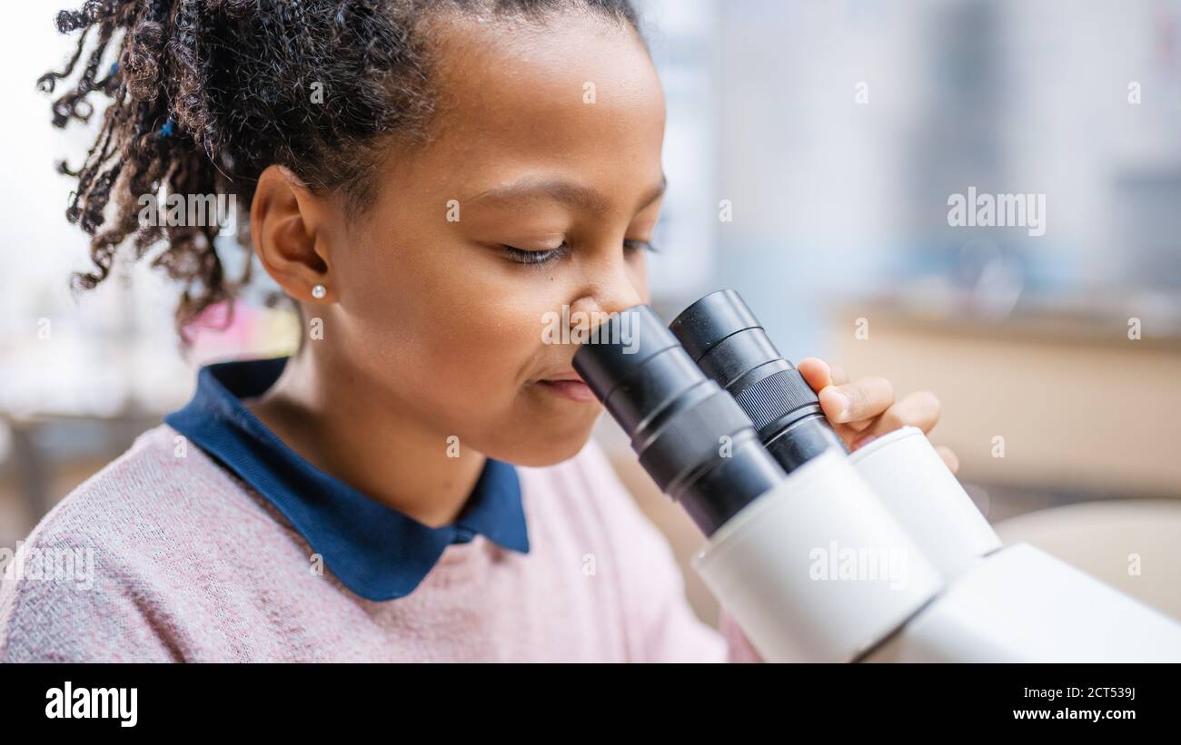 Portrait of Smart Little Schoolgirl Looking Under the Microscope. In