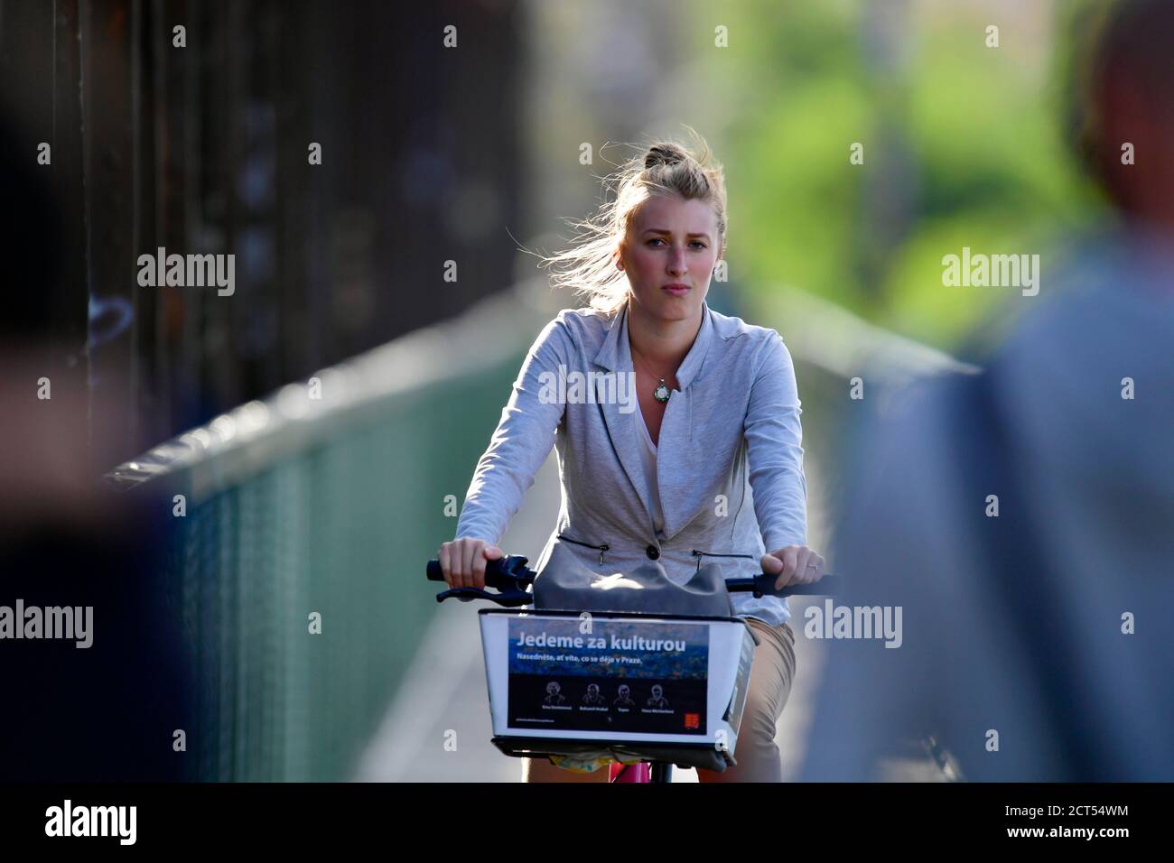a blond girl riding a bike across the bridge Stock Photo