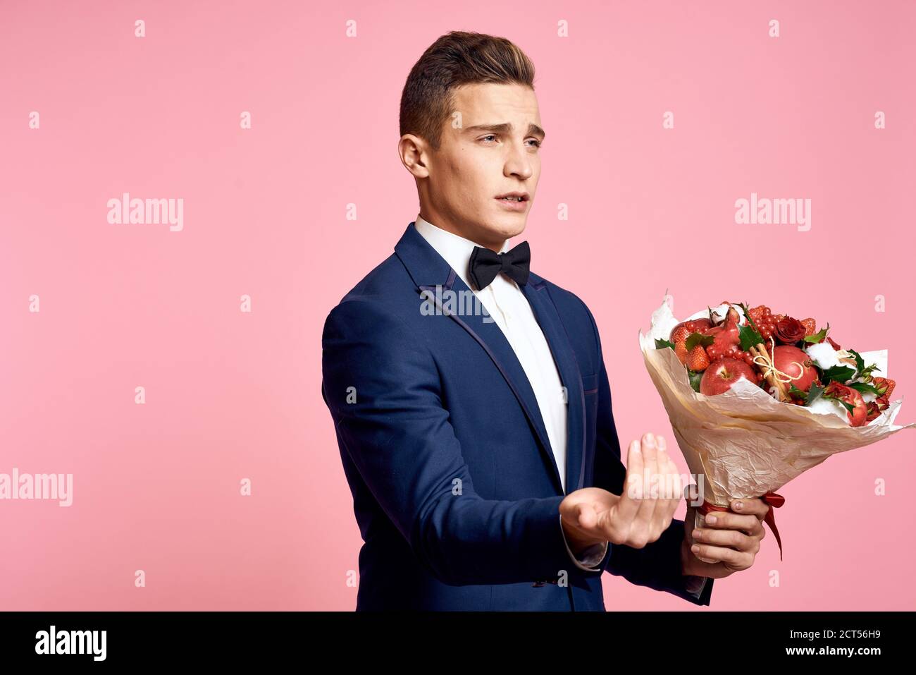 Handsome man in a classic suit with a bouquet of flowers on a pink ...