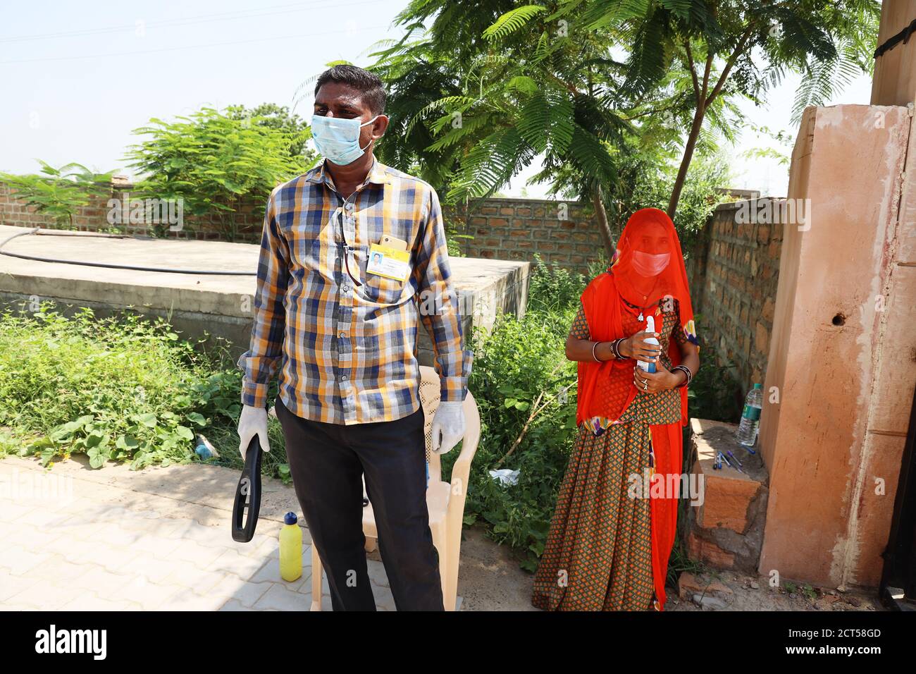 Jodhpur, Rajasthan, India, September 13,2020: Seutiry guard with metal detector and woman with sanitizer wearing mask standing at school entrance wait Stock Photo