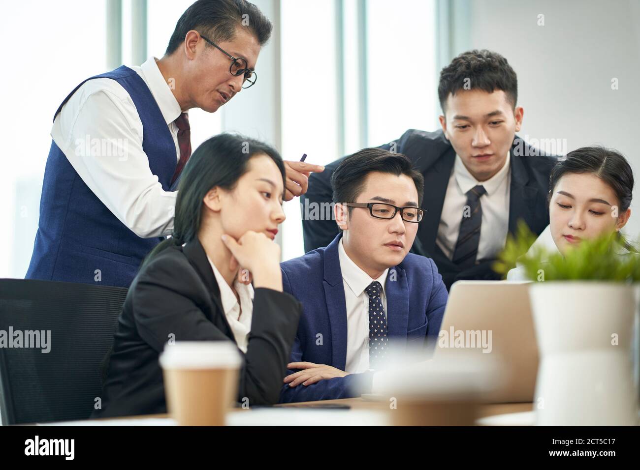 team of asian corporate executives meeting to discussing business using laptop computer Stock Photo