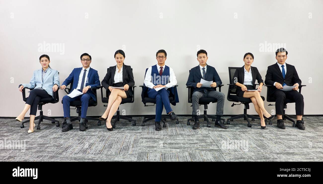 asian business people waiting in line for job interview looking at camera Stock Photo