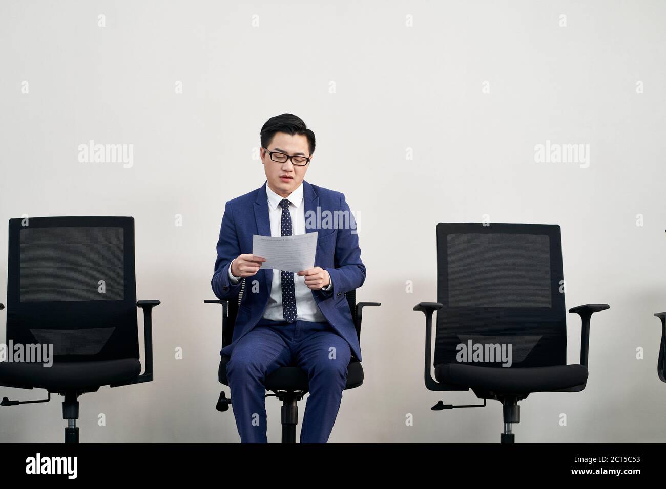 young asian male job seeker preparing for interview while waiting in line Stock Photo