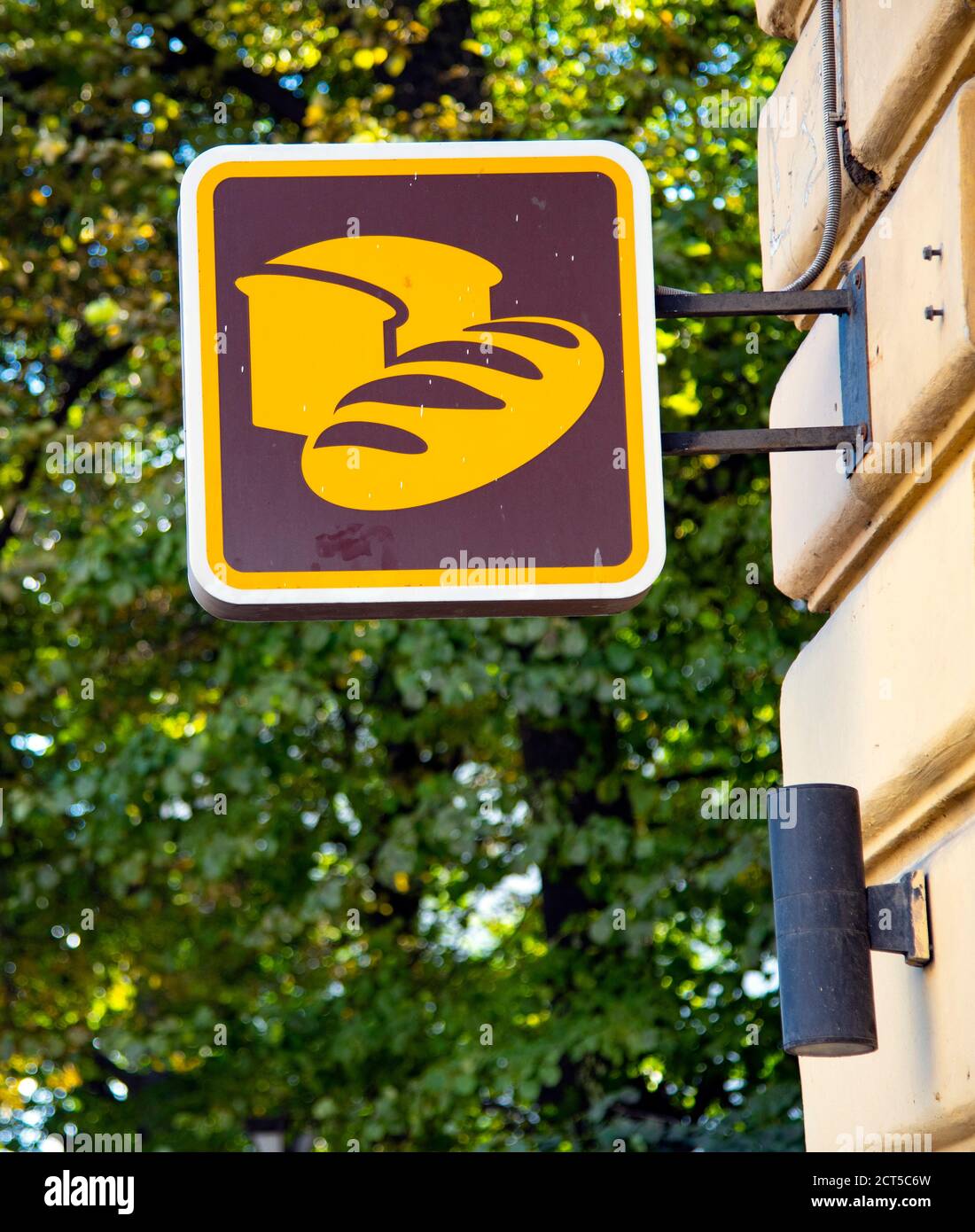 A Square Sign With Bread Painted On It Hangs On The Corner Of The