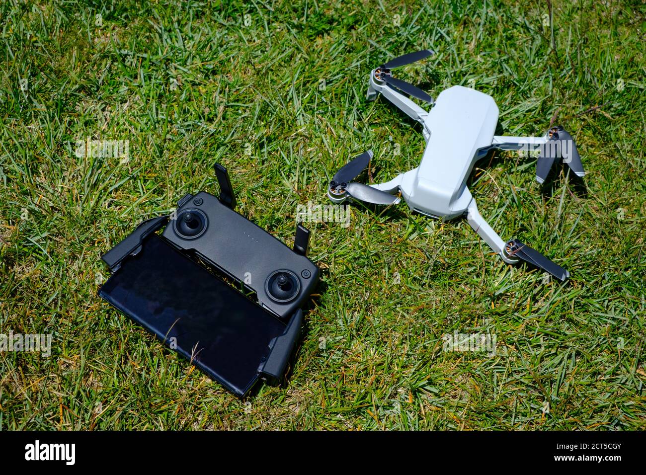Portable mini drone with its remote control attached to a smartphone on a grass background Stock Photo