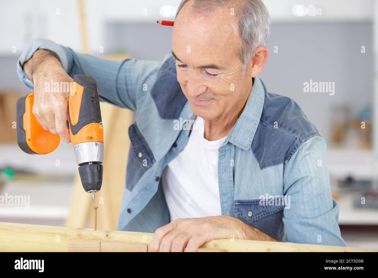 senior man using a power drill Stock Photo