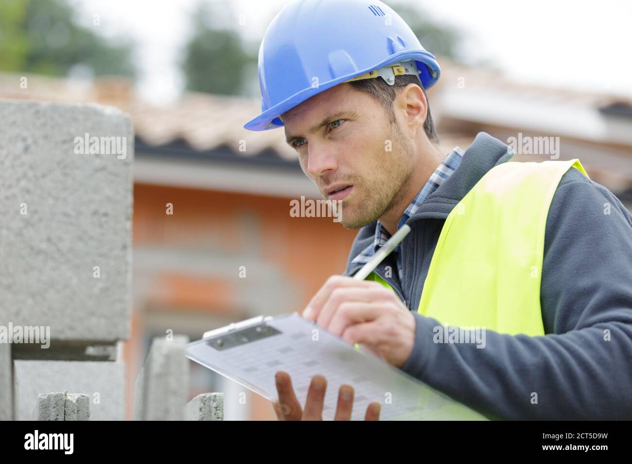 handsome builder writing on clipboard Stock Photo