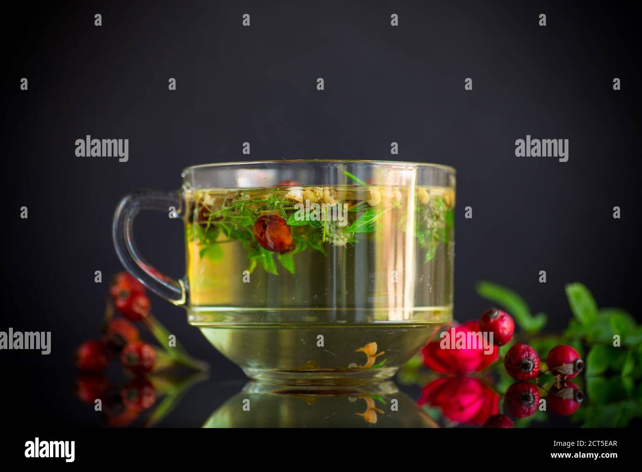 hot herbal tea from various herbs in glass cup on black background ...