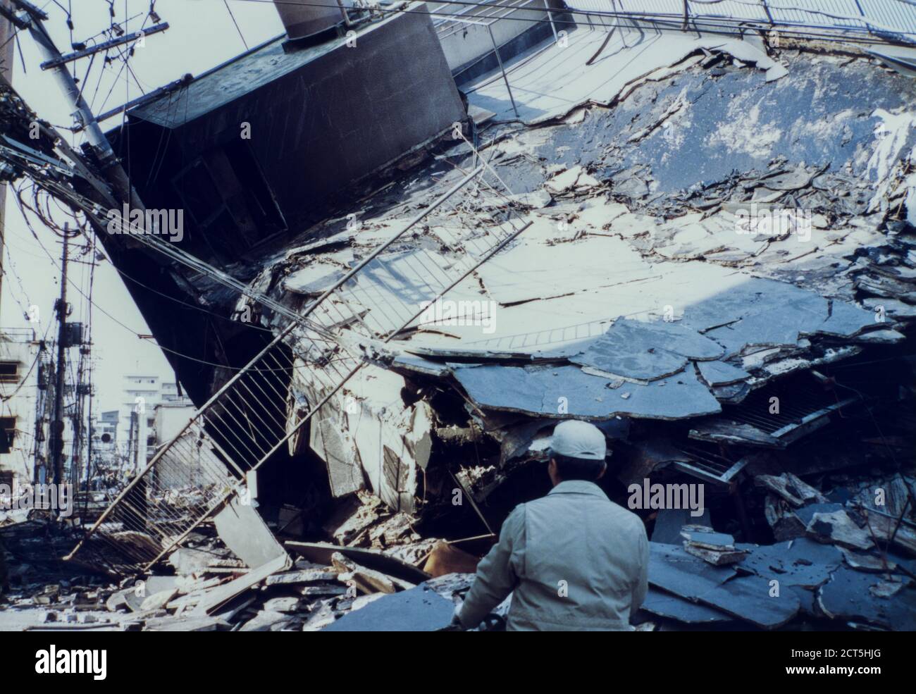 Man stops and looks upon collapsed building from the damage caused by the 1995 Great Hanshin Earthquake in Kobe, Japan Stock Photo