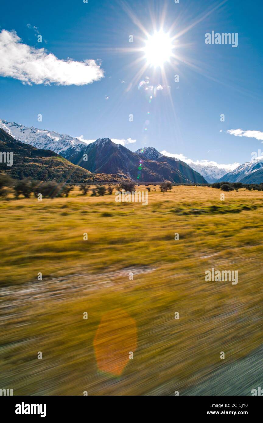 Driving on a road trip adventure through the Snow Capped Mountains landscape of Aoraki Mount Cook National Park, South Island New Zealand Stock Photo