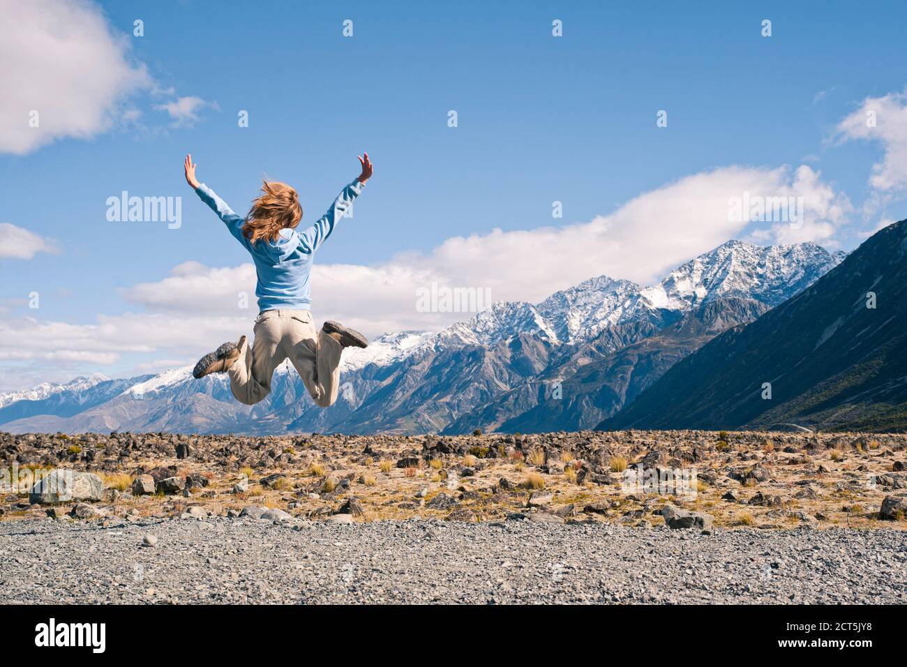 Young Woman Jumping for Joy in Aoraki Mount Cook National Park, South Island, New Zealand Stock Photo