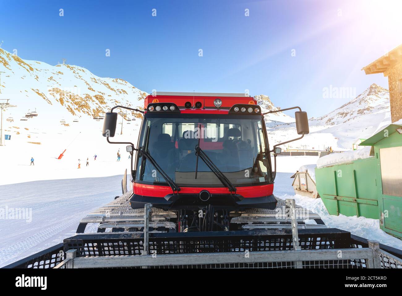 Red modern snowcat ratrack with snowplow snow grooming machine preparing ski slope piste hill at