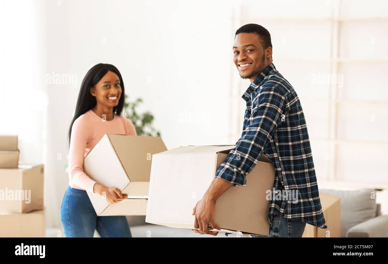 Black millennial couple carrying carton boxes in their new apartment on moving day Stock Photo