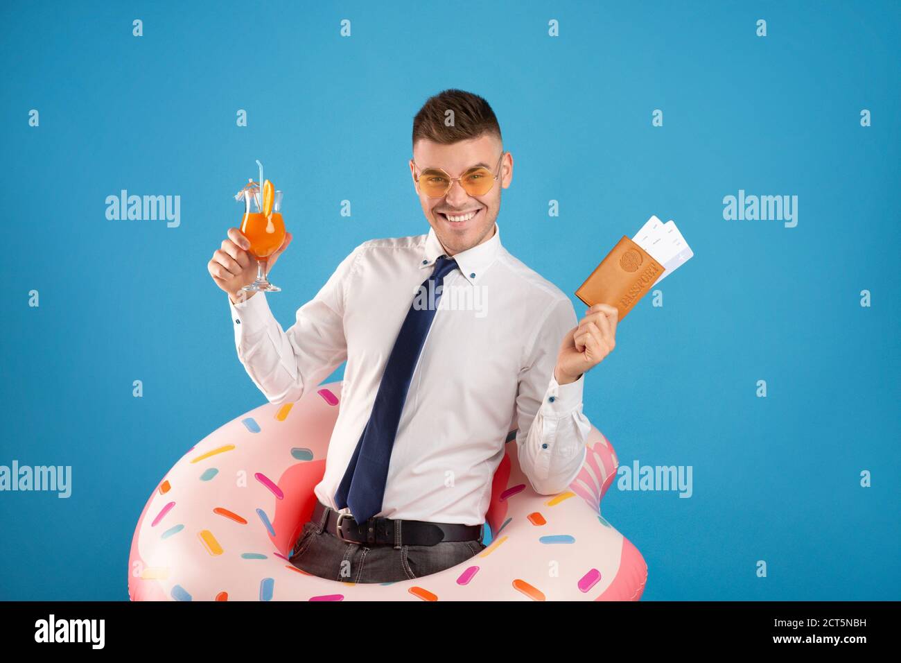 Happy office worker with passport, tickets, inflatable ring and cocktail dreaming of summer vacation, blue background Stock Photo