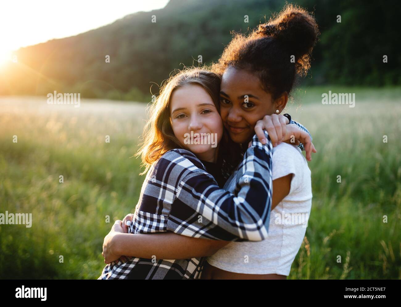 Front view of young teenager girls friends outdoors in nature, hugging. Stock Photo