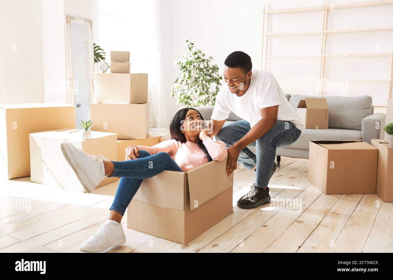 Cheerful African American couple having fun in their new home on moving day Stock Photo