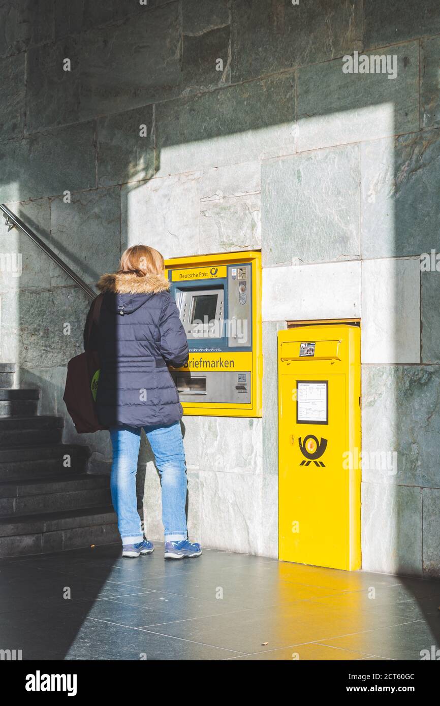Bamberg/Germany-2/1/19: rear view of a woman withdrawing cash in the ATM of Deutsche Postbank on a street in a german town. Postbank is the retail ban Stock Photo