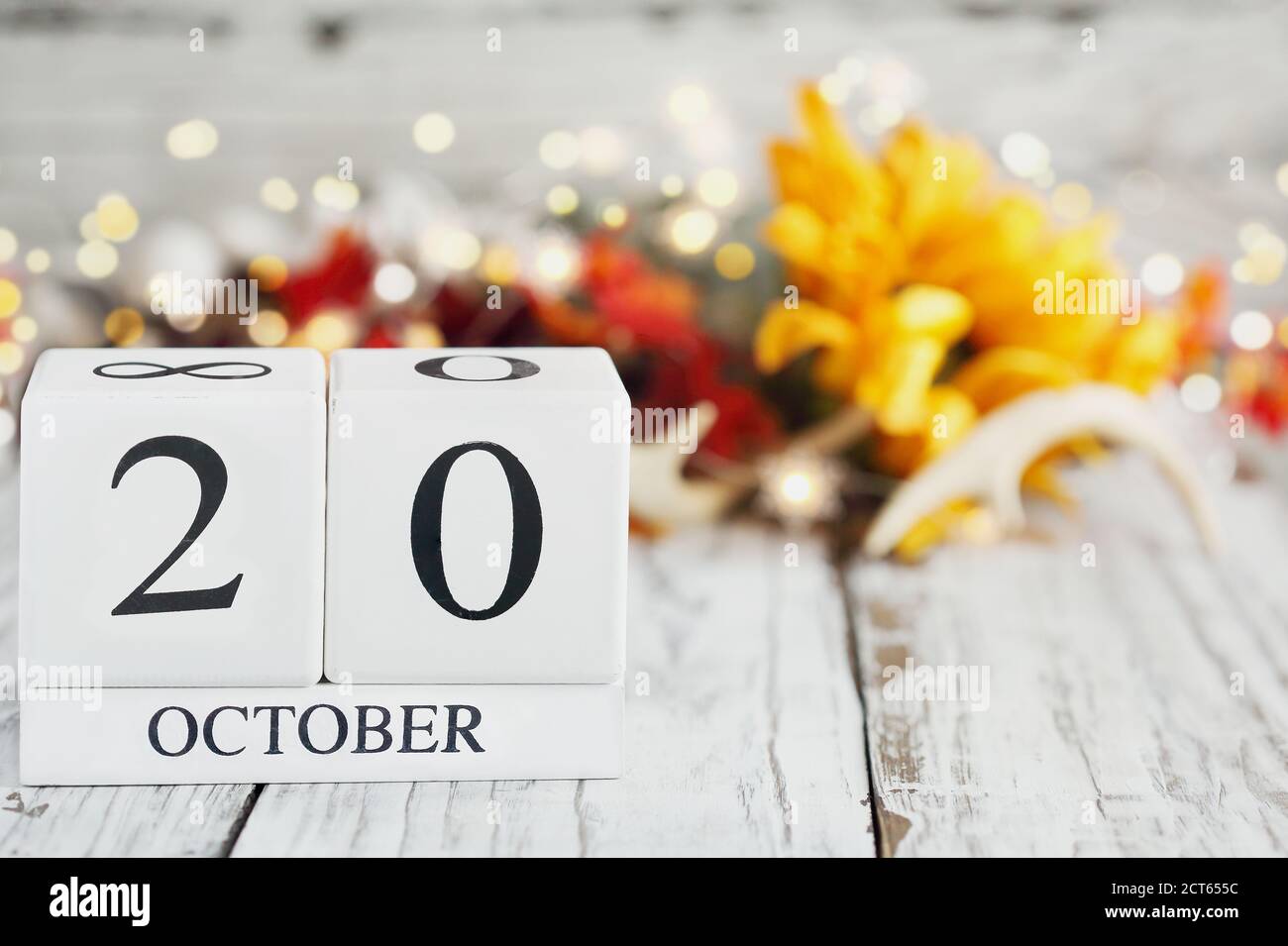 White wood calendar blocks with the date October 20th and autumn decorations over a wooden table. Selective focus with blurred background. Stock Photo