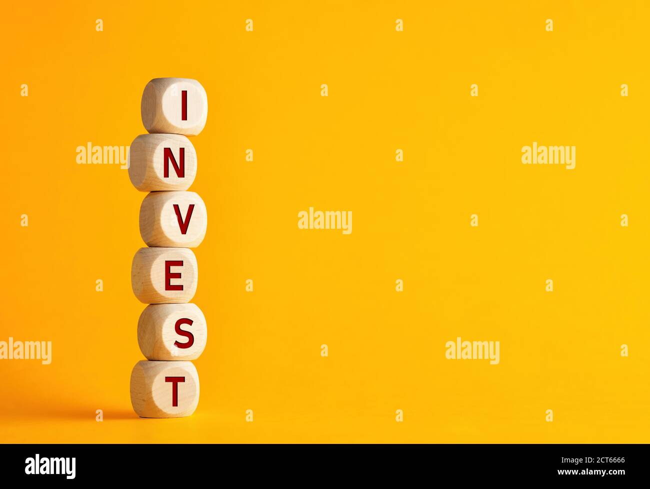 The word invest on wooden cubes against yellow background. Financial investment growth or investment decision in business concept. Stock Photo
