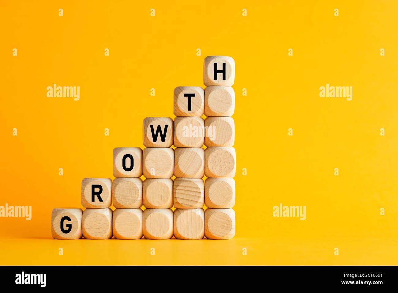 The word growth on stacked wooden cubes against yellow background. Financial or business growth concept. Stock Photo