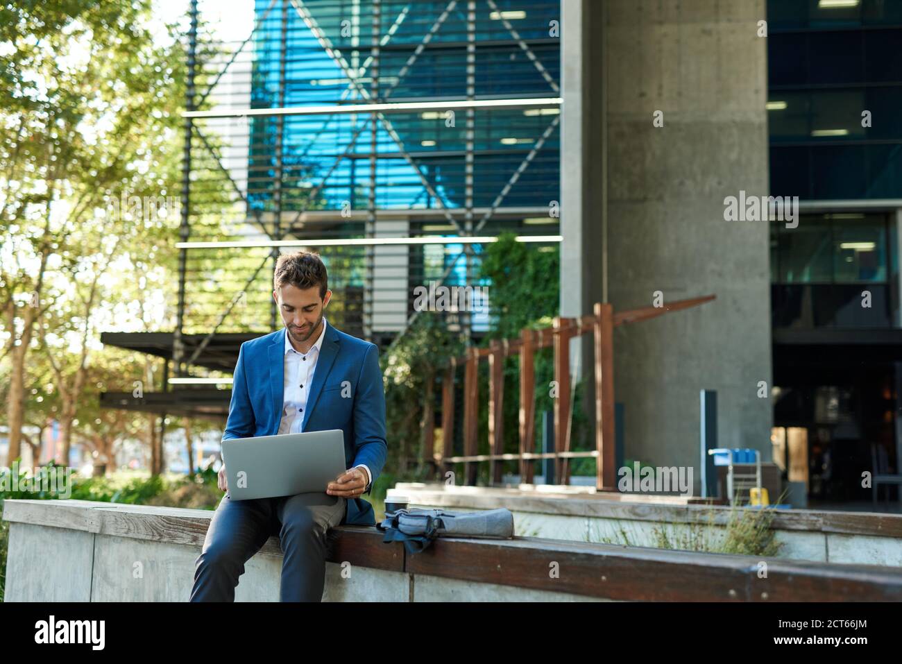 Businessman sitting outside his office building using a laptop Stock ...