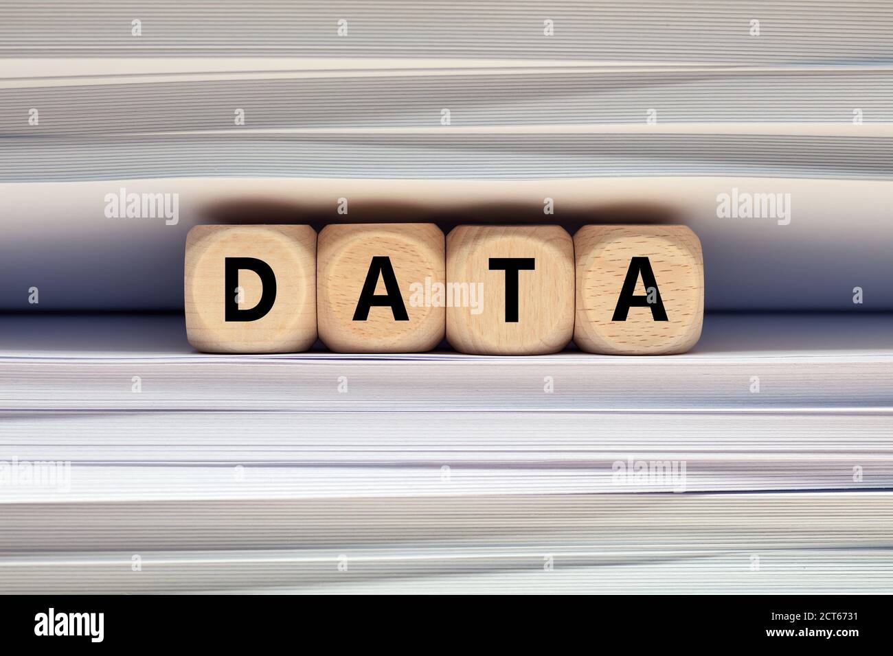 The word data on wooden cubes against pile of files and folders background. Data collection for research or business investment decisions concept. Stock Photo