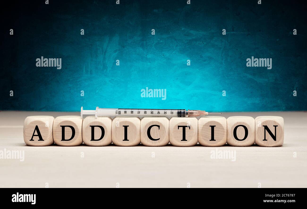 The word addiction on wooden cubes with a syringe. Drug or substance addiction concept. Stock Photo