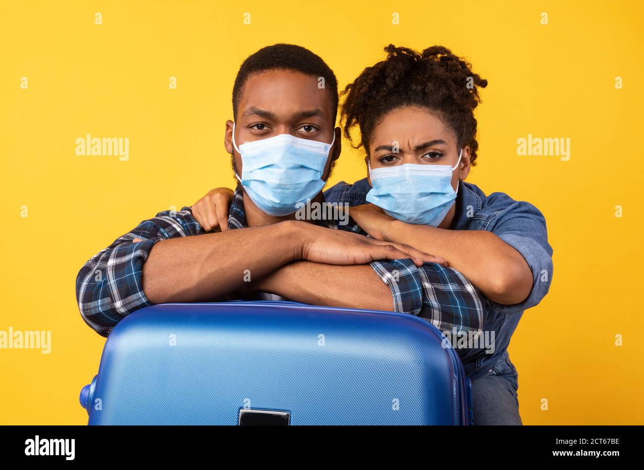 Black Travelers Couple Wearing Masks Posing With Suitcase In Studio Stock Photo