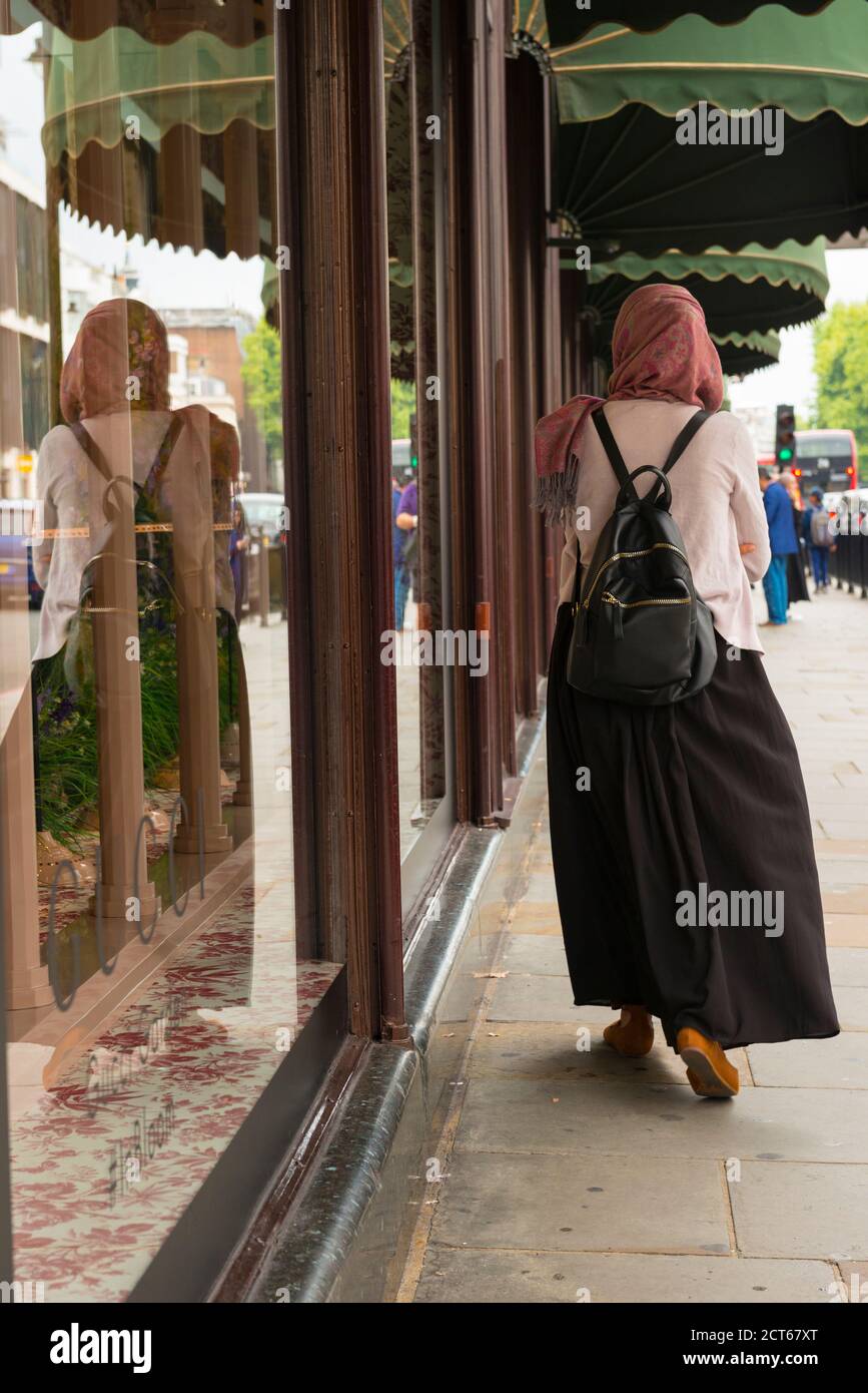 London West End Knightsbridge street scene Arab Muslim woman hijab abaya rucksack haversack walking shopping shop window Stock Photo