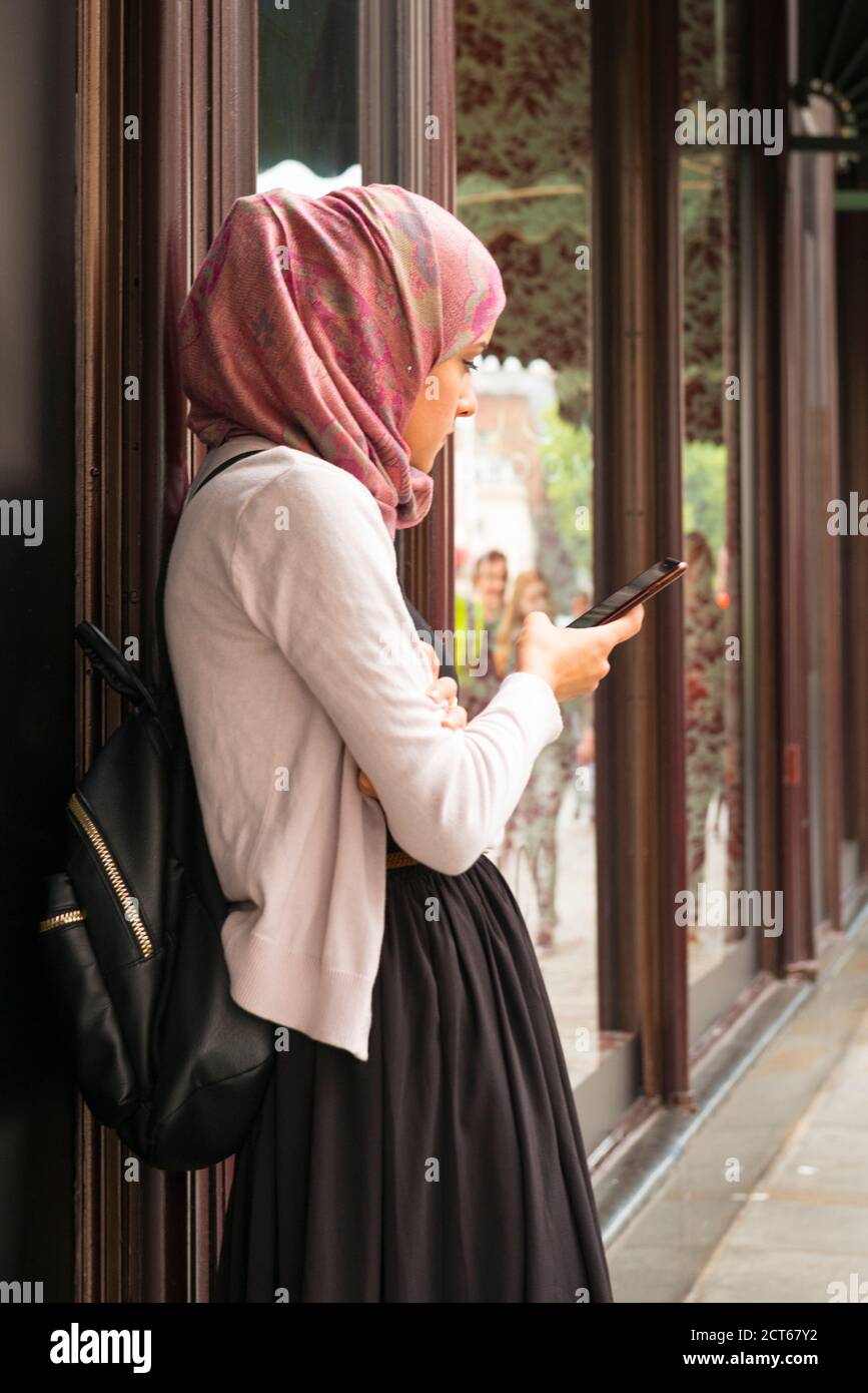 London West End Knightsbridge street scene Arab Muslim woman hijab abaya shopping shop window cell mobile phone Stock Photo