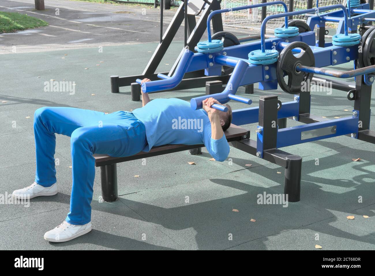 sporty slim man doing bench press using outdoors gym equipment. making an  effort to lift a bar. motivation and progress concept. chest exersice.  outdoors gym Stock Photo - Alamy