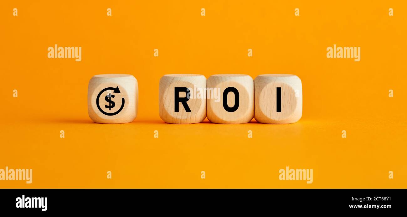 The word ROI return on investment written on wooden cubes with on yellow background. Profit or loss analysis in business and finance concept. Stock Photo
