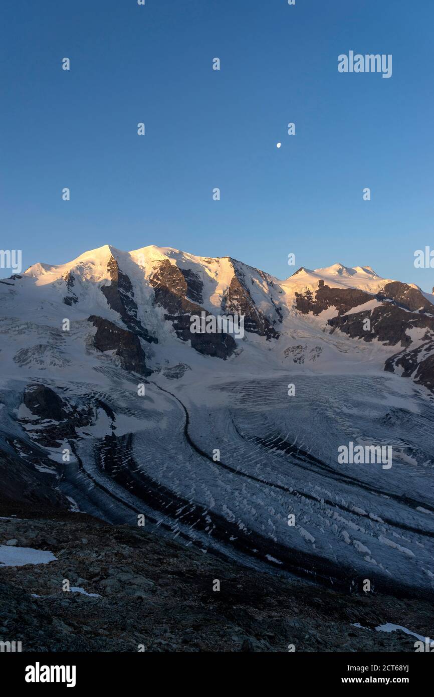 Der dreigipflige Piz Palü und die ebenfalls dreigipflige Bellavista (von links). Davor der Persgletscher. Darüber der Mond. Bei Sonnenaufgang. Obereng Stock Photo