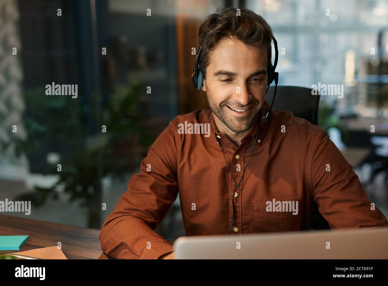 Smiling businessman talking on a headset with a client Stock Photo
