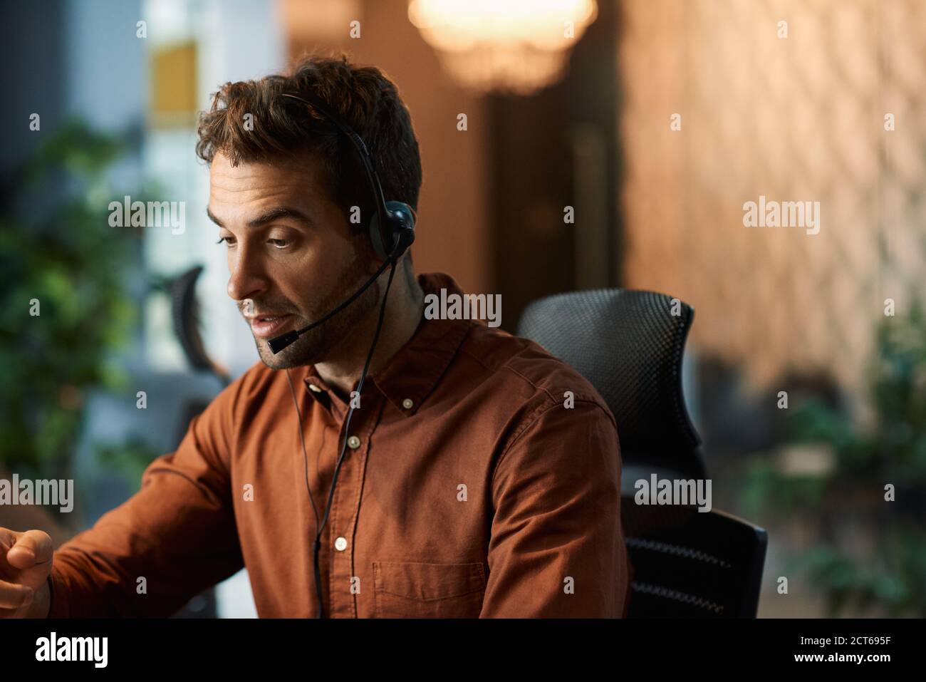 Businessman talking on a headset while working late Stock Photo