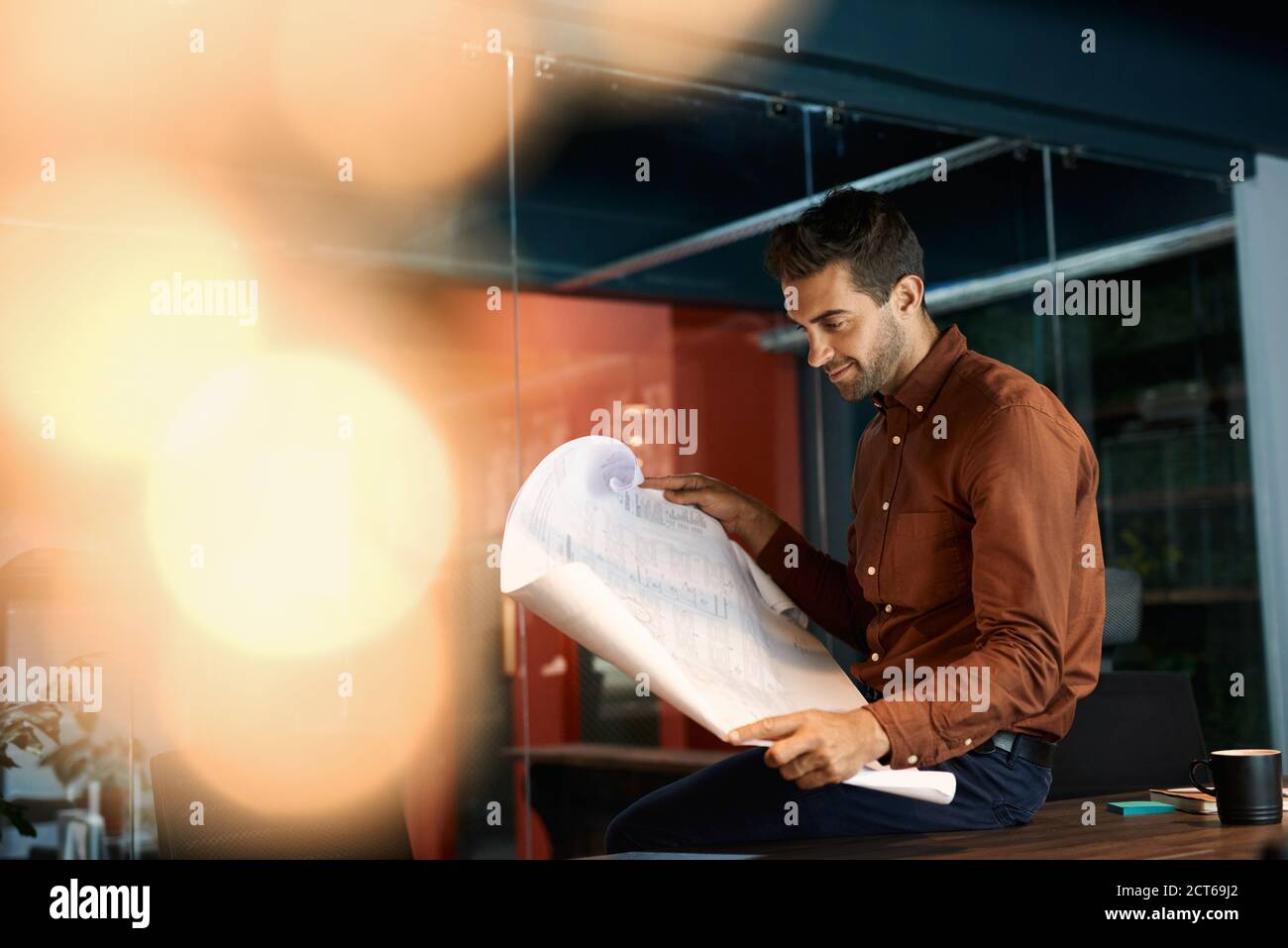 Architect reading blueprints while working late in his office Stock Photo
