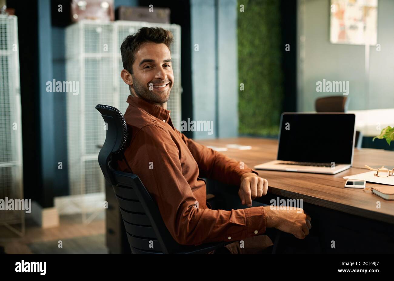 Smiling businessman working late at his office desk Stock Photo